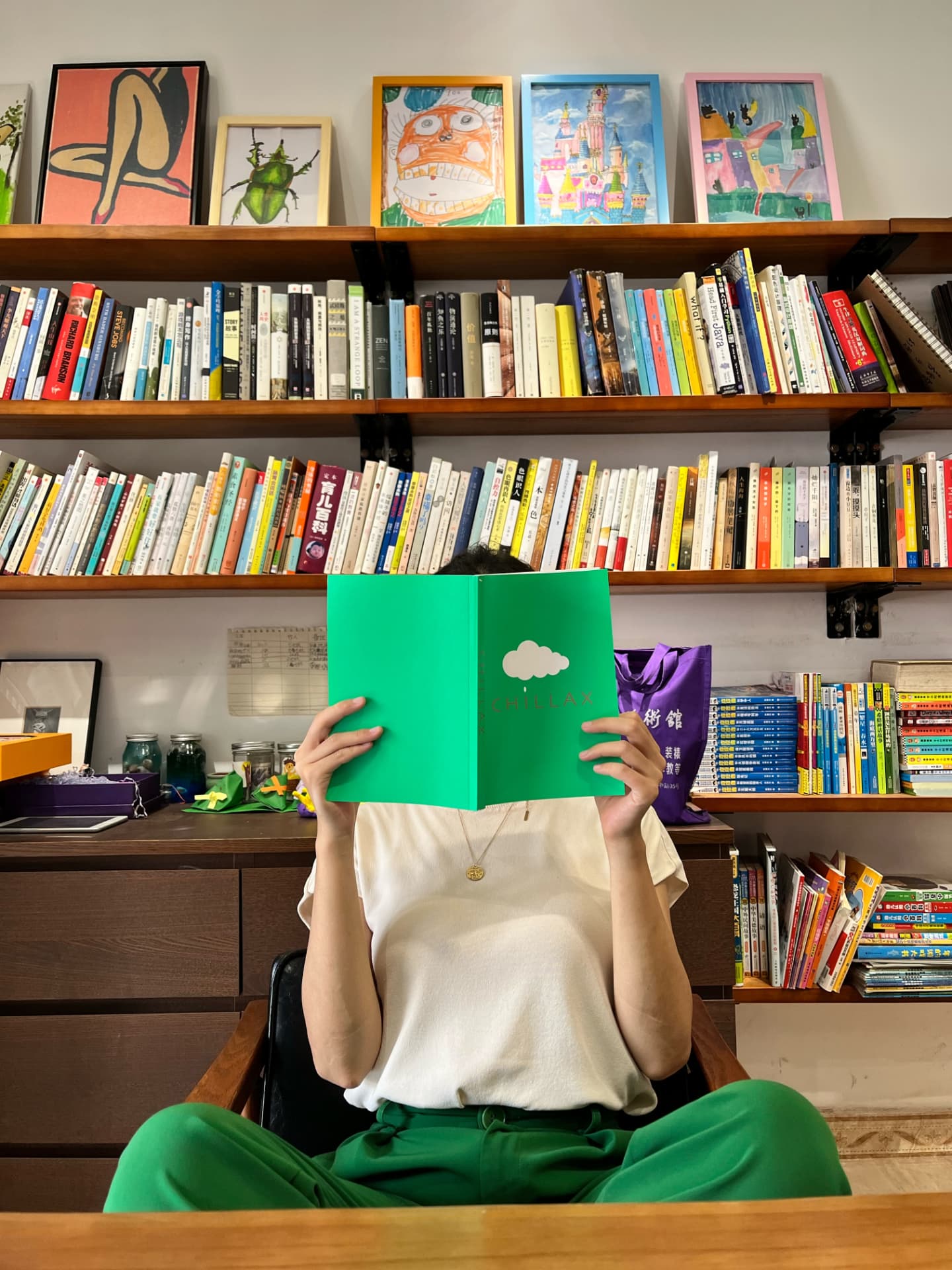 Xiaoen reading a book in front of a wall of bookshelves