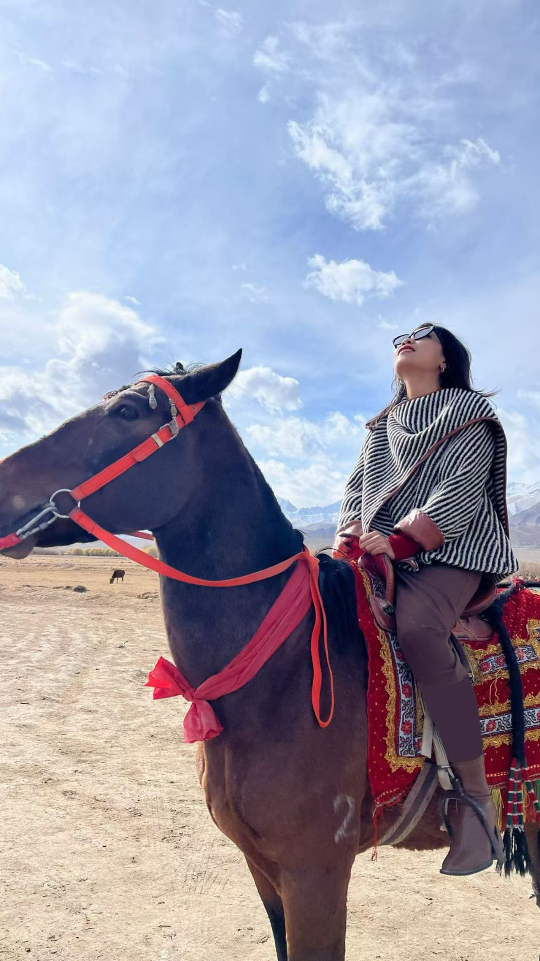 Xiaoen on horseback beneath open sky and distant mountains